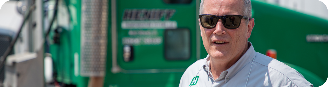 A man in front of green semi-truck cab