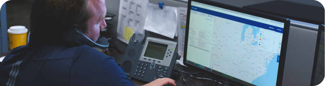 Services - VISISHIP TMS Man working at computer while talking on the phone at the Heniff facility